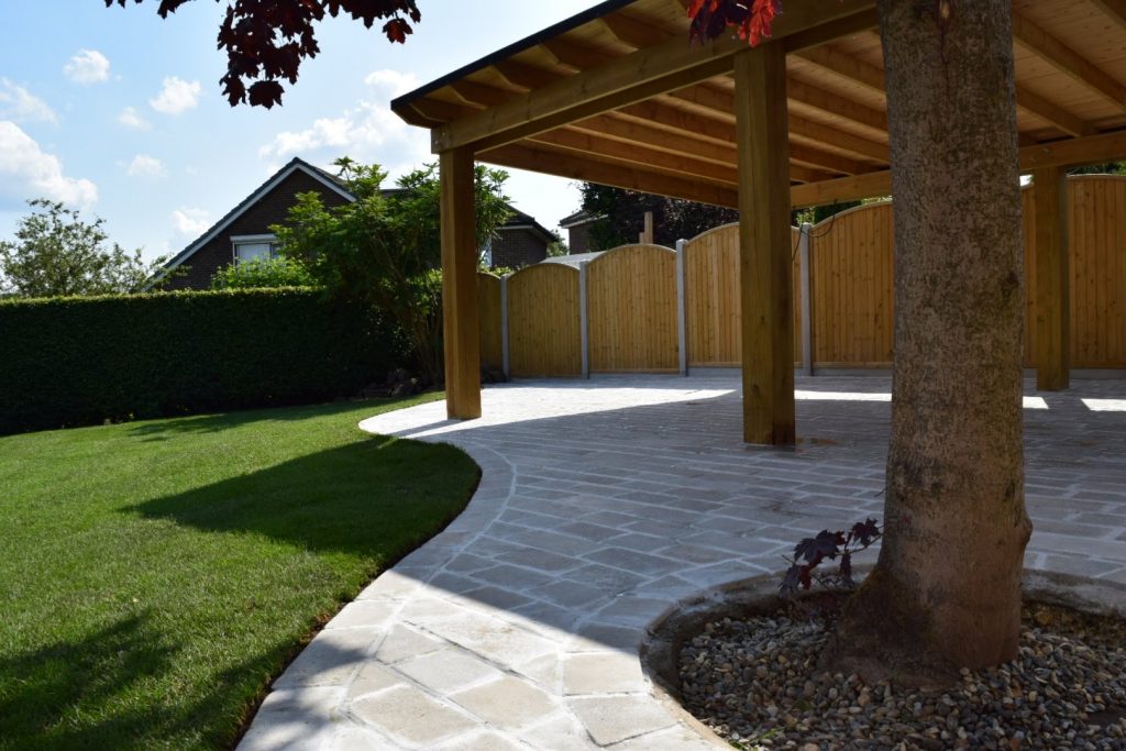 Artisan Cobble patio featuring a tree ring and bespoke design hardwood Pergola, crafted with heritage materials to create a stunning Landscape in the Leeds & Yorkshire area.