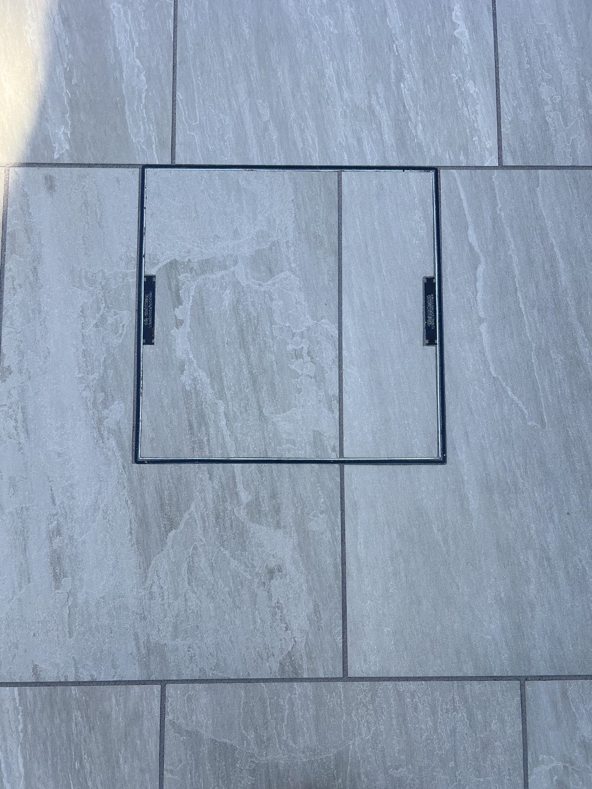 modern landscaping with expert level craftsmanship- porcelain paving cut perfectly, showcased by this "invisible" manhole cover, Stonemasonry & Landscaping Services in Leeds & West Yorkshire at their best!