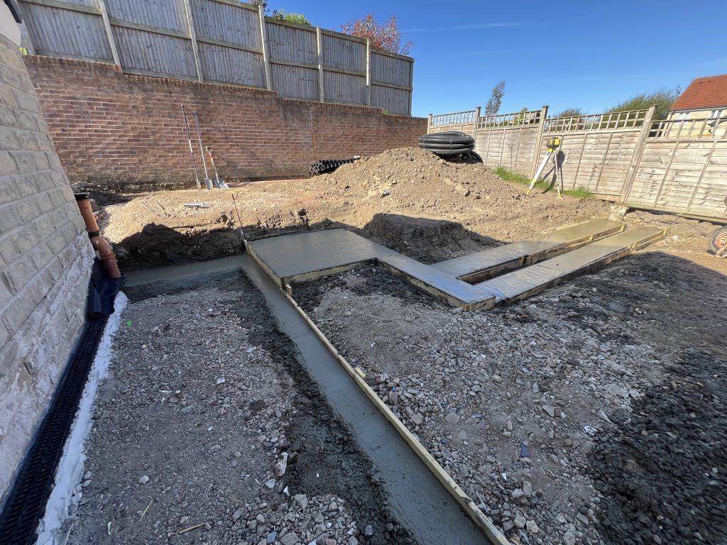 Before: Functional Landscaping retaining feature in progress: Dug out, concrete footings shuttered and poured and ready to start Stonewalling. 