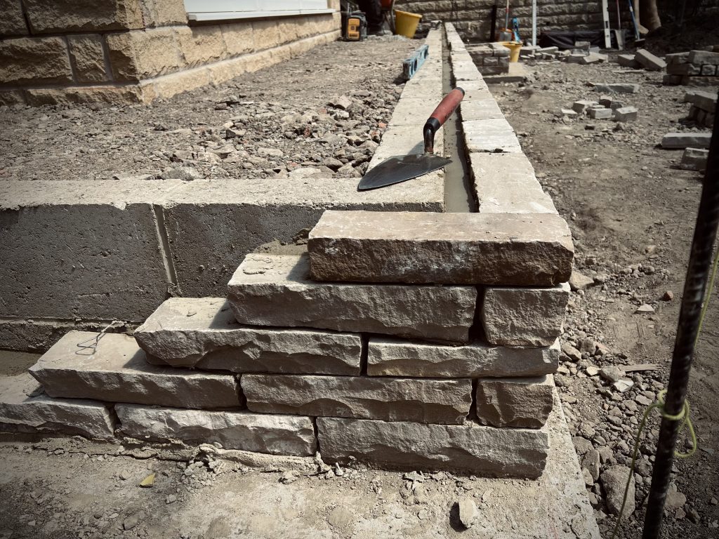 Drystone effect double skinned retaining feature wall built in sandstone. Showcasing our Stonemasonry and Landscaping in Leeds & West Yorkshire.