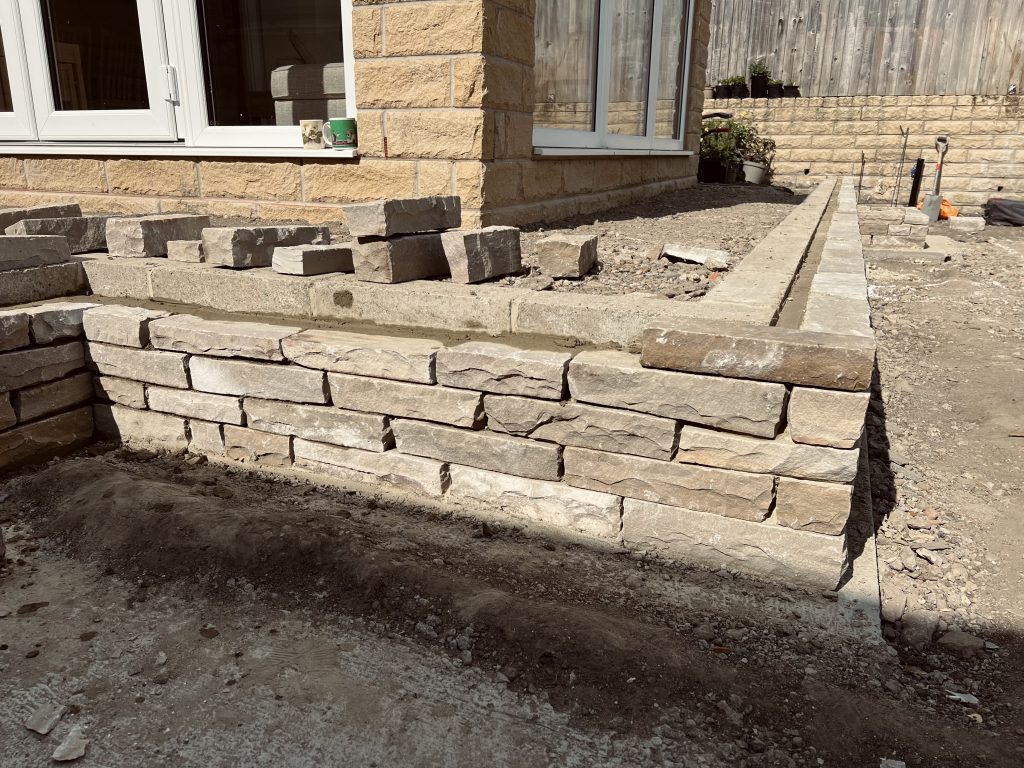 Drystone effect double skinned retaining feature wall built in sandstone. Showcasing our Stonemasonry in Leeds & West Yorkshire.