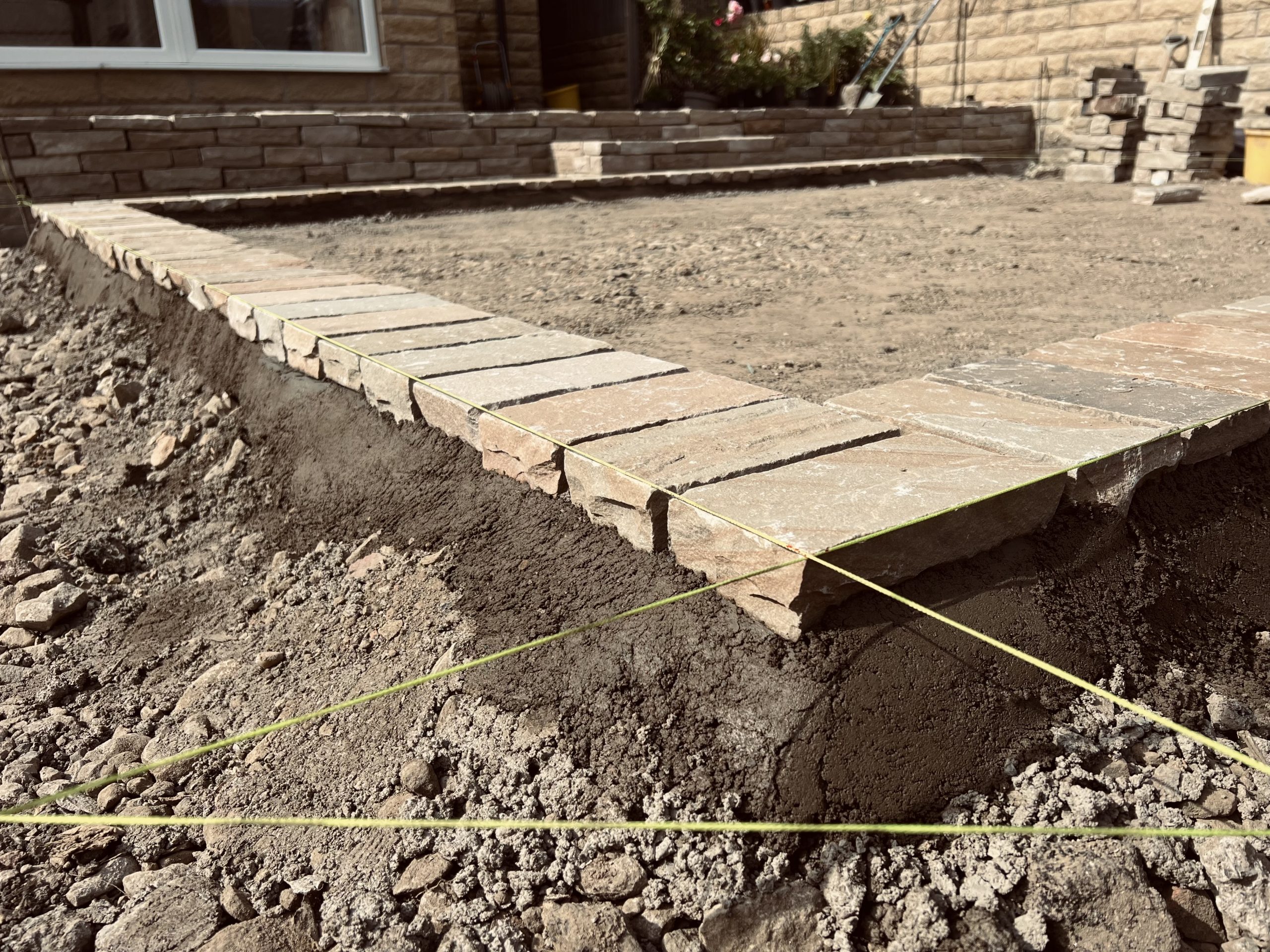 Sandstone cobble Setts in progress in Yorkshire, with string lines forming a perfect square border for a herringbone pattern infill.