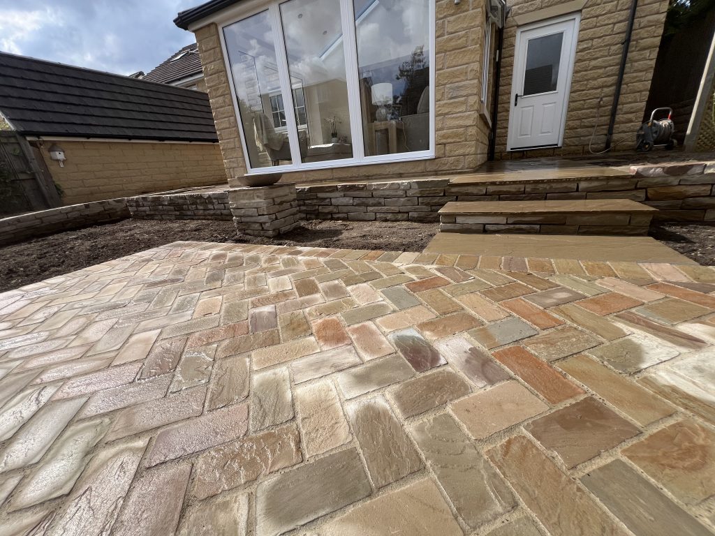 Full Stonemasonry & Landscaping Project in Leeds including retaining wall, Herringbone natural stone cobbles, feature bird bath, steps and curved paths, showcasing Hardscaping at its best by Strata Stoneworks.